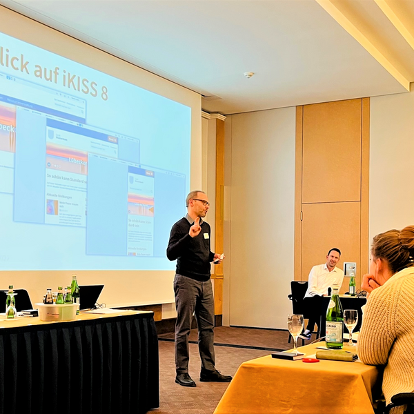 Das Bild zeigt den Advantic Produktmanager Marc Buscher vor der Präsentationsleinwand. Diese zeigt drei Varianten der neuen iKISS-Version 8.